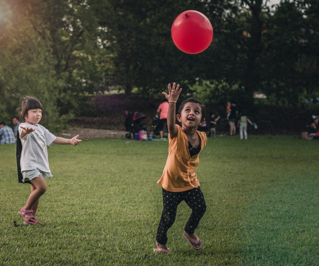 Two girls playing with a balloon in a park